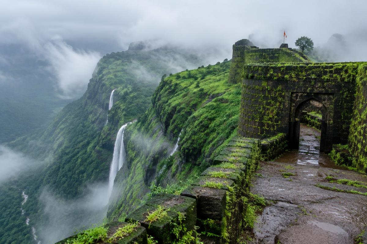 Moss-covered hill fort in the Western Ghats with monsoon waterfalls